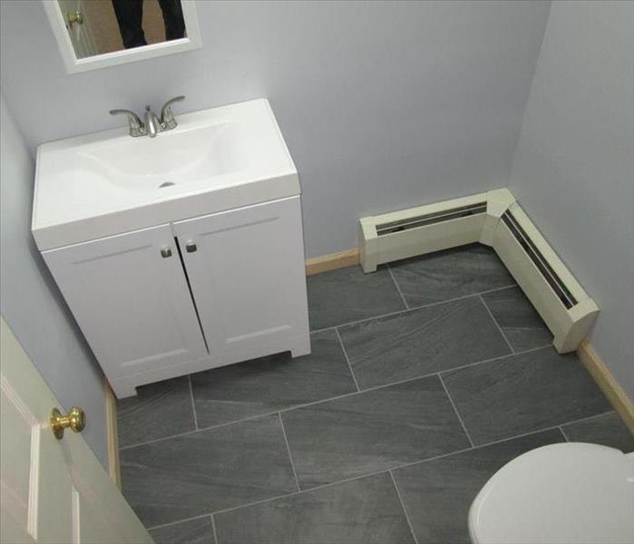 bathroom, sparkling white vanity, toilet bowl, baseboard heaters, servpro logo, gray nice floors