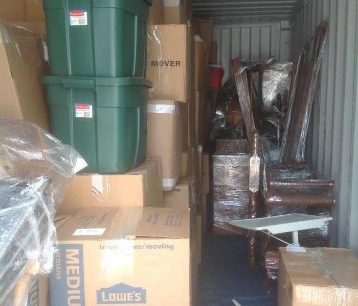 Storage container packed with moving boxes, plastic storage bins, and carefully wrapped furniture