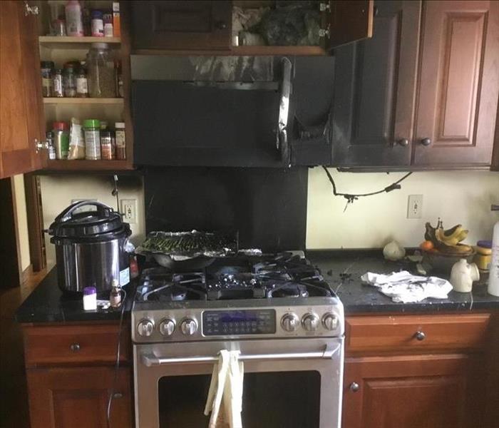 Kitchen fire, burnt cabinetry and appliances, walls covered in soot, and contents of cabinets.
