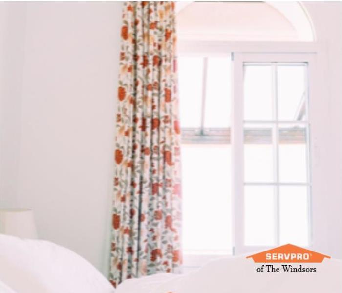 White Bedroom with white linens, Orange and white floral drapery and orange SERVPRO Logo