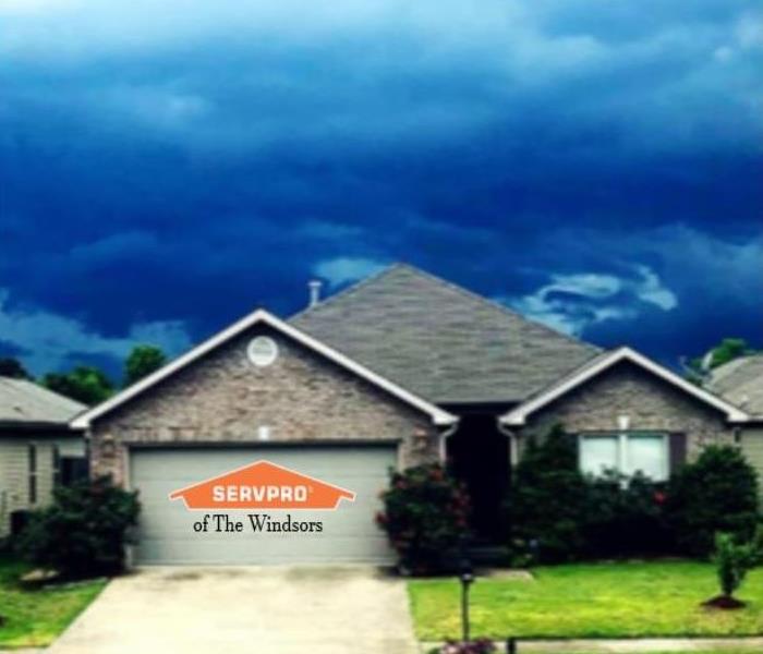 House, front lawn, sky with clouds showing impending bad weather, servpro logo.